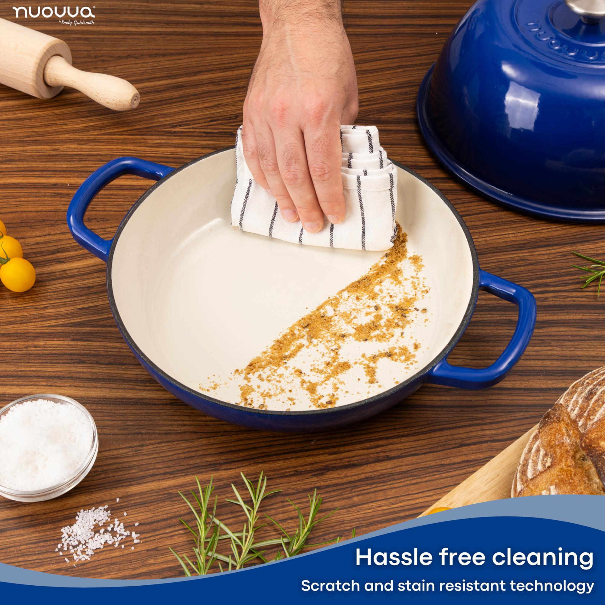 Person cleaning a blue enameled cast iron bread towel with a dish towel as it promises hassle free cleaning with scratch and stain resistant technology. 
